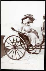 Un mannequin de mode assis dans une calèche tenant une ombrelle, 1902